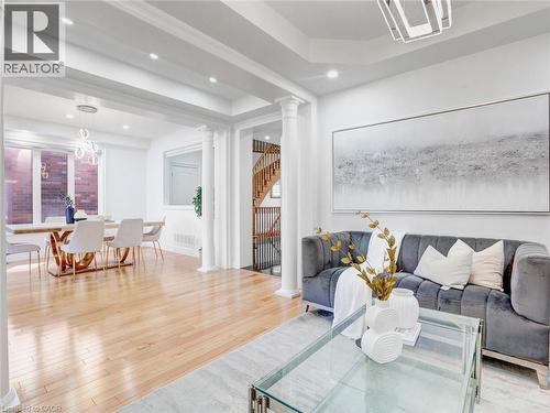 Open-concept living space featuring light wood-finish flooring, recessed lighting, decorative columns, and a visible dining area with a modern chandelier - 584 Pinery Trail, Waterloo, ON - Indoor