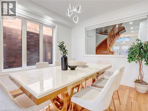 Dining area featuring a polished rectangular table with a gold-tone base, white wall paint, and wood-finish flooring - 584 Pinery Trail, Waterloo, ON - Indoor Photo Showing Dining Room
