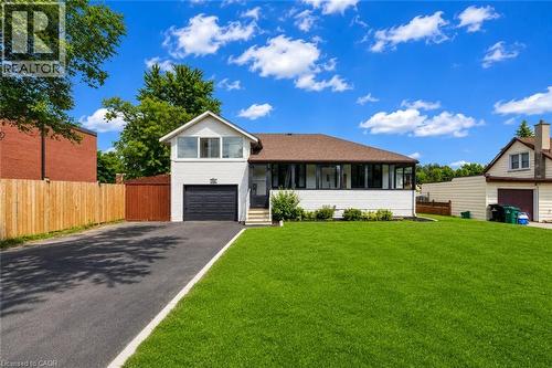 Contemporary split-level residence featuring a dark asphalt driveway, an integrated garage with a dark door, and a contrasting white exterior with dark trim - 182 Avalon Place, Kitchener, ON - Outdoor