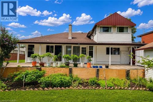 Rear exterior featuring a spacious concrete patio, a tiered garden bed, and a manicured lawn - 182 Avalon Place, Kitchener, ON - Outdoor