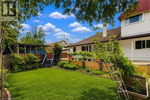 Expansive backyard featuring a manicured lawn, tiered landscaping with established plantings, and a raised wood deck with privacy screen - 182 Avalon Place, Kitchener, ON - Outdoor