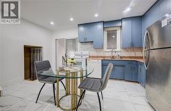 Functional kitchen space featuring blue cabinetry, white appliances, a stainless steel refrigerator, and a white tile floor - 