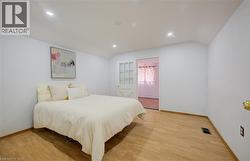 Spacious room featuring wood-finish flooring, recessed lighting, and white wall finishes - 