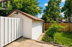 Detached outbuilding with white siding and a brown shingle roof - 