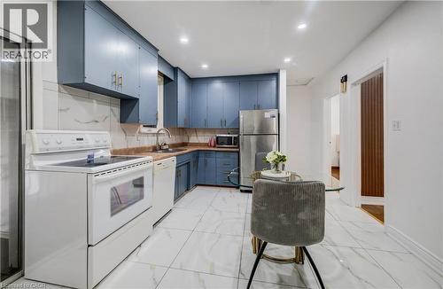 Kitchen featuring blue cabinetry, white appliances, white and gray veined floor tiling, recessed lighting, and a stainless steel refrigerator - 182 Avalon Place, Kitchener, ON - Indoor Photo Showing Kitchen