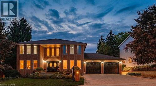 Brick-clad exterior with multiple large windows, double entry doors, and a paver driveway leading to a two-car garage - 28 Walnut Drive, Guelph, ON - Outdoor