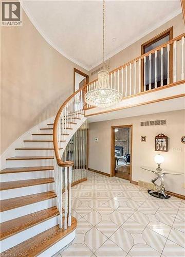 Elegant curved staircase featuring warm wood treads, white painted risers, and polished wood handrails with white balusters - 28 Walnut Drive, Guelph, ON - Indoor Photo Showing Other Room