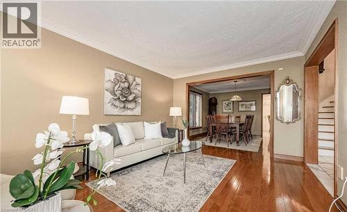Hardwood flooring, crown molding, and a cased opening leading to a dining space with a chandelier - 28 Walnut Drive, Guelph, ON - Indoor Photo Showing Living Room