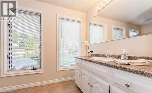 White vanity with an integrated sink, polished chrome faucet, and a flecked countertop - 28 Walnut Drive, Guelph, ON - Indoor Photo Showing Bathroom