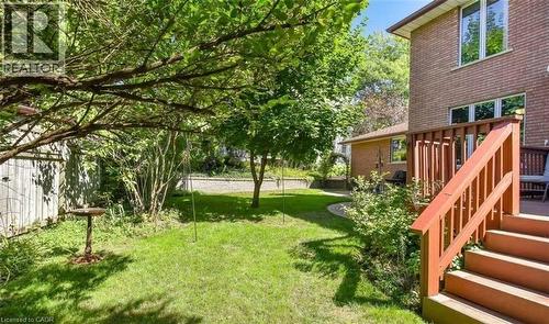 Mature landscaping with established shade trees and lush lawn anchors this residential backyard - 28 Walnut Drive, Guelph, ON - Outdoor