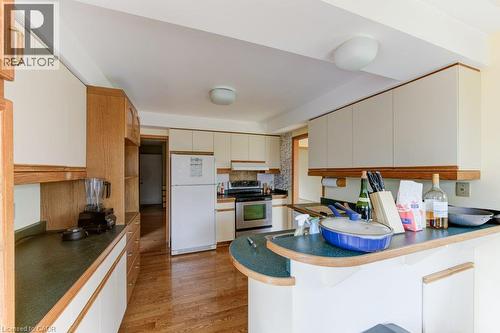 Kitchen featuring wood-finish flooring, white cabinetry with wood trim, and a built-in breakfast bar with a speckled countertop - 27 Walmer Gardens, London, ON - Indoor Photo Showing Kitchen