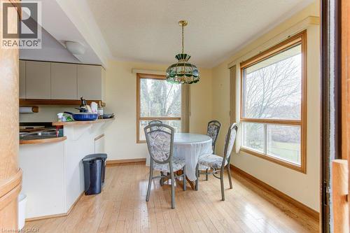 Dining area featuring wood-finish flooring, two large windows with wood trim, and a decorative pendant light fixture - 27 Walmer Gardens, London, ON - Indoor Photo Showing Dining Room