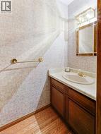 Vanity with an integrated sink and light-toned countertop, wood-finish flooring, and a wall-mounted light fixture - 