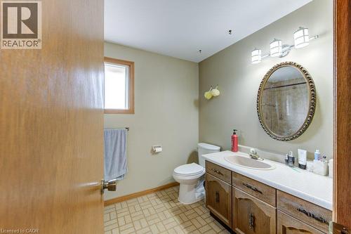 Bathroom featuring a vanity with a white countertop, an oval mirror, an overhead three-light fixture, and a window with wood trim - 27 Walmer Gardens, London, ON - Indoor Photo Showing Bathroom