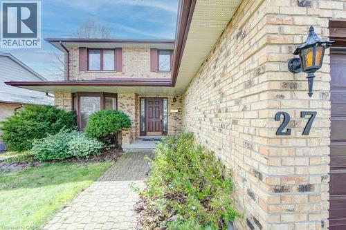 Brick exterior featuring a bay window, dark brown front door, and a paver walkway - 27 Walmer Gardens, London, ON - Outdoor