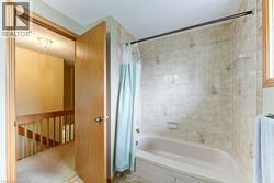 Bathroom featuring a bathtub with tiled surround, light-colored wall tiles with decorative accents, and an overhead bath rod - 