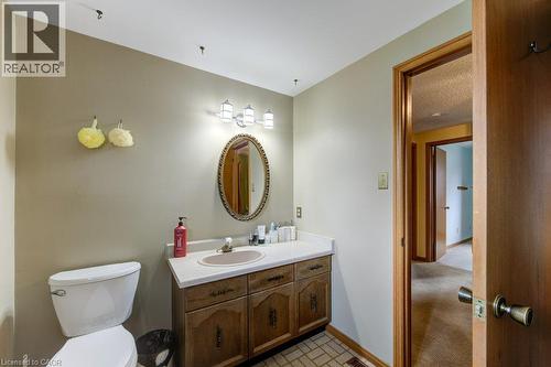 Bathroom featuring a wood-finish vanity with a white countertop and integrated sink, an oval mirror, and a three-light vanity fixture - 27 Walmer Gardens, London, ON - Indoor Photo Showing Bathroom