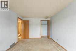 Carpeted room featuring light blue walls, a textured ceiling, a flush-mount light fixture, and a built-in closet with a wooden door - 