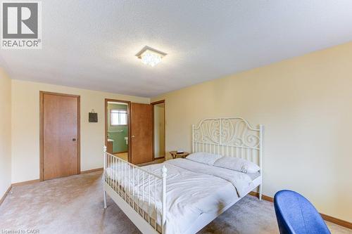 Carpeted room featuring a ceiling-mounted light fixture, light-colored walls, and wood-finish doors - 27 Walmer Gardens, London, ON - Indoor Photo Showing Bedroom