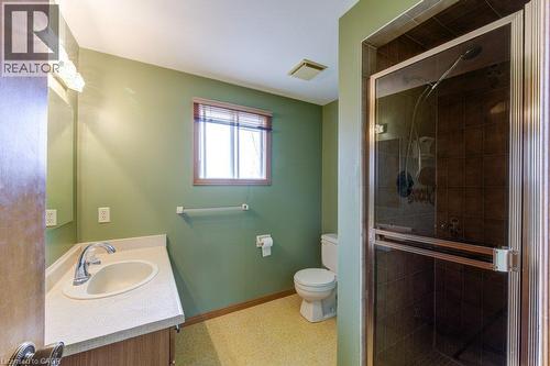 Spa-inspired primary bathroom featuring soft sage green walls, a large walk-in shower with glass enclosure and tile surround, white vanity with round vessel sink and chrome fixtures, and yellow-toned - 27 Walmer Gardens, London, ON - Indoor Photo Showing Bathroom