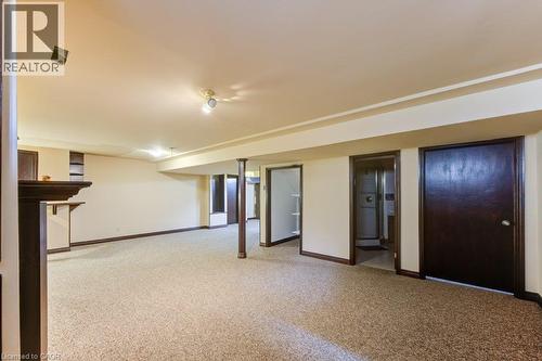 Spacious finished interior space with light-toned carpeting, recessed lighting, support columns, built-in shelving, and dark-stained trim and doors - 27 Walmer Gardens, London, ON - Indoor Photo Showing Other Room