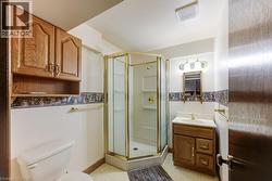 Bathroom with a corner shower enclosure featuring a gold-tone frame and a built-in vanity with a white countertop - 