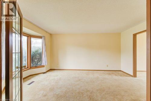 Spacious room featuring a bay window with wood trim, neutral wall color, and carpeted flooring - 27 Walmer Gardens, London, ON - Indoor Photo Showing Other Room