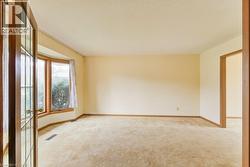 Spacious room featuring a bay window with wood trim, neutral wall color, and carpeted flooring - 