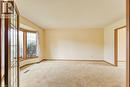 Spacious room featuring a bay window with wood trim, neutral wall color, and carpeted flooring - 27 Walmer Gardens, London, ON  - Indoor Photo Showing Other Room 