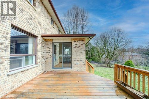 Exterior brick facade featuring a wood deck with wood railings, sliding glass door access, and an expansive grassy area - 27 Walmer Gardens, London, ON - Outdoor With Deck Patio Veranda