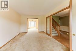 Expansive carpeted room featuring light-toned walls and wood-finish baseboards - 