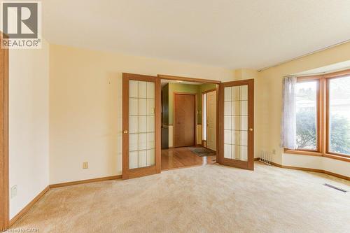 Open room with neutral carpeting, featuring a bay window with wood trim - 27 Walmer Gardens, London, ON - Indoor Photo Showing Other Room