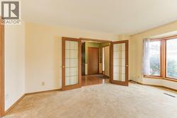 Open room with neutral carpeting, featuring a bay window with wood trim - 