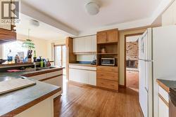 Kitchen featuring wood-finish flooring, a double basin sink, and built-in cabinetry with both natural wood and painted finishes - 