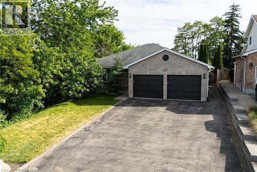 Spacious two-car garage with dark panel doors, wide asphalt driveway, and stone veneer exterior - 907 Doon Village Road, Kitchener, ON - Outdoor