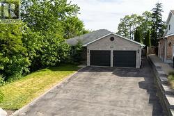 Spacious two-car garage with dark panel doors, wide asphalt driveway, and stone veneer exterior - 