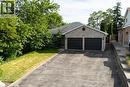 Spacious two-car garage with dark panel doors, wide asphalt driveway, and stone veneer exterior - 907 Doon Village Road, Kitchener, ON  - Outdoor 