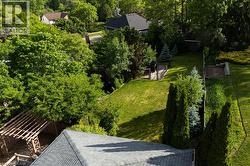 Expansive rear yard featuring a manicured lawn, established landscaping, a wooden pergola, and a visible storage shed - 