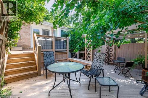 Expansive composite deck featuring multiple entertaining zones with a round glass-top dining table, lounge seating, and integrated pergola structures - 907 Doon Village Road, Kitchener, ON - Outdoor With Deck Patio Veranda With Exterior