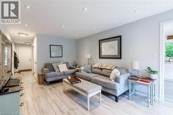 Bright, open-concept living area showcasing light wood-finish flooring, soft blue-gray walls, and recessed ceiling lighting - 