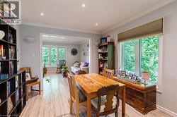 Open-concept dining area featuring wood-finish flooring, recessed lighting, and a large window with privacy blinds - 
