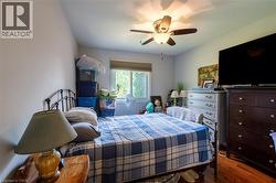Bright bedroom featuring hardwood flooring, ceiling fan with integrated lighting, and ample natural light from sliding glass doors - 