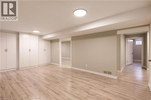 Spacious room featuring wood-finish flooring, extensive built-in white cabinetry, recessed lighting, neutral wall paint, and white trim - 907 Doon Village Road, Kitchener, ON - Indoor