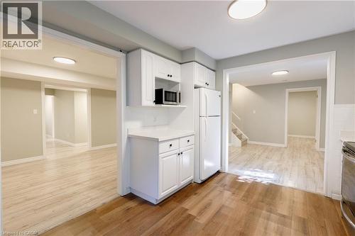 Bright, open-concept living space featuring wood-finish flooring throughout, recessed ceiling lighting, and white cabinetry with stainless steel appliances - 907 Doon Village Road, Kitchener, ON - Indoor Photo Showing Other Room