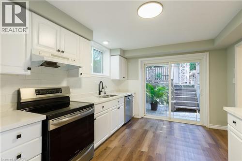 Bright and updated kitchen featuring white cabinetry with hardware accents, stainless steel appliances, white subway tile backsplash, and white quartz countertops - 907 Doon Village Road, Kitchener, ON - Indoor Photo Showing Kitchen With Double Sink