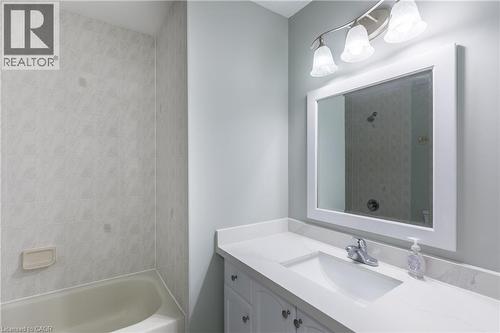 Contemporary bathroom featuring a framed mirror with integrated lighting, white quartz countertop with rectangular undermount sink, gray cabinetry with hardware accents, chrome faucet fixture, and adj - 907 Doon Village Road, Kitchener, ON - Indoor Photo Showing Bathroom