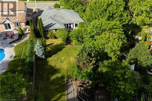 Expansive rear yard featuring abundant mature trees, a manicured lawn, and sloped landscaping - 907 Doon Village Road, Kitchener, ON - Outdoor