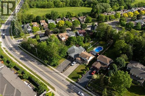 Aerial view of this residential estate showcasing a sprawling manicured lawn, mature tree-lined landscaping, in-ground swimming pool with surrounding hardscape, multi-car driveway, and substantial bri - 907 Doon Village Road, Kitchener, ON - Outdoor With View