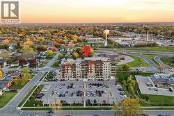 Modern multi-story building featuring extensive balconies, a prominent parking area, and surrounding green spaces - 