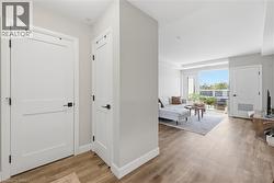 Interior hallway with wood-finish flooring and white paneled doors featuring matte black hardware - 